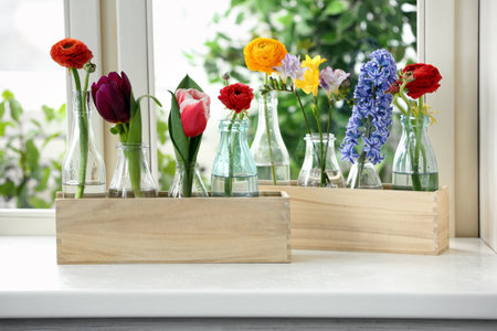 Beautiful spring flowers in wooden crates on window sillの写真素材