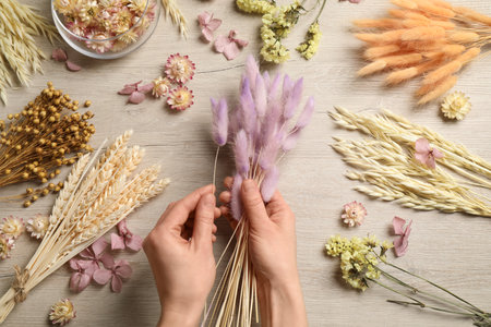 Florist making bouquet of dried flowers on white wooden table, top viewの写真素材