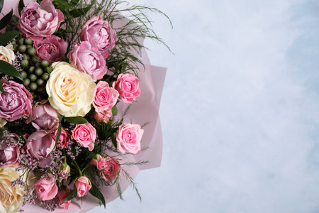 Beautiful bouquet with roses on light blue background, closeup. Space for textの写真素材