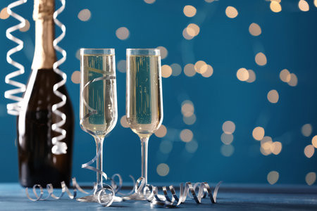 Glasses and bottle of champagne with serpentine streamers against blurred lights. Space for textの写真素材
