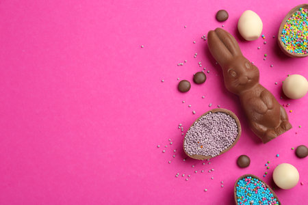 Flat lay composition with chocolate Easter bunny, candies and eggs on pink background. Space for textの写真素材