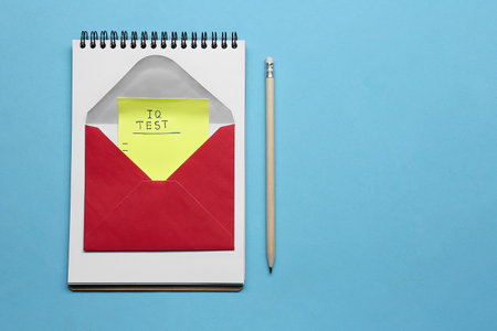 Note with words IQ Test in envelope, notebook and pencil on light blue background, flat lay. Space for textの写真素材