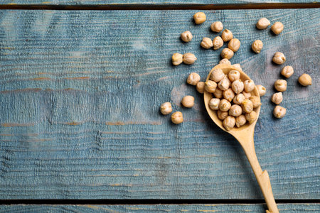 Raw chickpeas with spoon on blue wooden table, flat lay. Space for textの写真素材