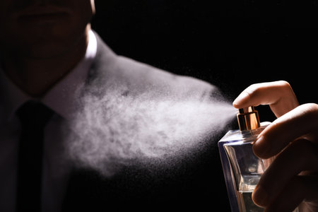 Man spraying luxury perfume on black background, closeupの写真素材
