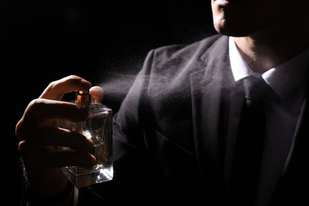 Man spraying luxury perfume on black background, closeupの写真素材