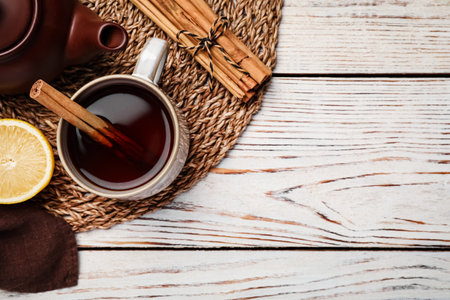 Delicious hot tea with cinnamon and lemon on white wooden table, flat lay. Space for textの写真素材