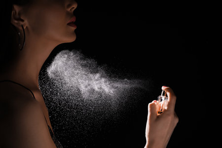 Woman spraying luxury perfume on black background, closeupの写真素材