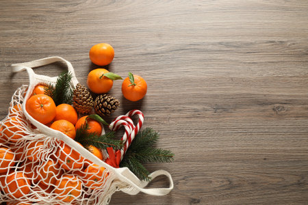 Flat lay Christmas composition with fresh tangerines in mesh bag on wooden table. Space for textの写真素材