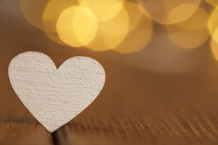 White heart on wooden table against festive lights, space for text. St. Valentine's dayの写真素材