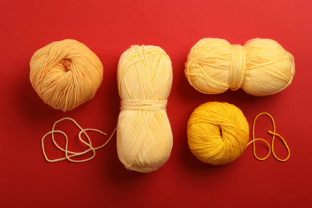 Soft woolen yarns on red background, flat layの写真素材