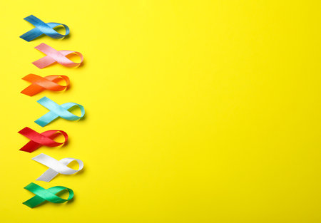 Colorful ribbons on yellow background, flat lay with space for text. World Cancer Dayの写真素材
