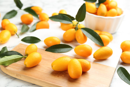 Fresh ripe kumquats and leaves on wooden boardの写真素材