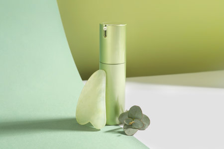 Jade gua sha tool, eucalyptus branch and cosmetic product on color backgroundの写真素材