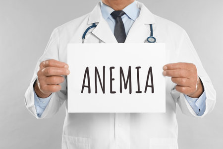 Doctor holding sign with word ANEMIA on light gray background, closeupの写真素材