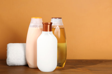 Different shower gel bottles with towel on wooden table. Space for textの写真素材