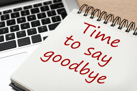 Notebook with phrase Time to say goodbye and laptop on table, closeupの写真素材