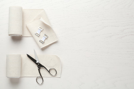 Medical bandage rolls and scissors on white wooden table, flat lay. Space for textの写真素材