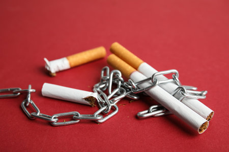Cigarettes and chains on red background. Quitting smoking conceptの写真素材