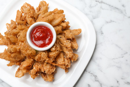 Fried blooming onion with dipping sauce served on white marble table, top view. Space for textの写真素材