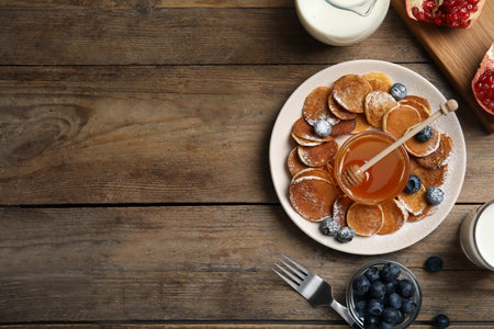 Delicious pancakes cereal with blueberries and honey served on wooden table, flat lay. Space for textの写真素材