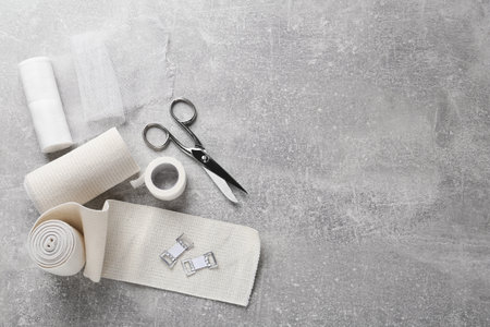 Medical bandage rolls, sticking plaster and scissors on gray table, flat lay. Space for textの写真素材