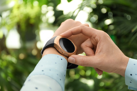 Mature woman using smart watch outdoors, closeupの写真素材