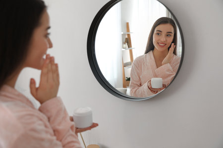 Young woman applying face cream at home. morning routineの写真素材