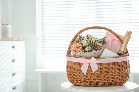 Wicker basket with gifts on table indoors. Space for textの写真素材