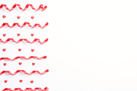 Red serpentine streamers and heart shaped confetti on white background, top viewの写真素材