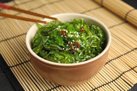Chopsticks with Japanese seaweed salad in bowl on table, closeupの写真素材
