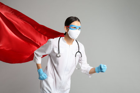 Doctor dressed as superhero posing on light gray background.の写真素材