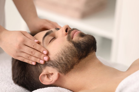 Young man receiving facial massage in beauty salon, closeupの写真素材