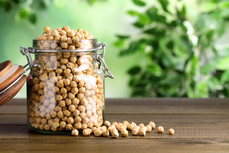 Raw chickpeas in jar on wooden table. Space for textの写真素材