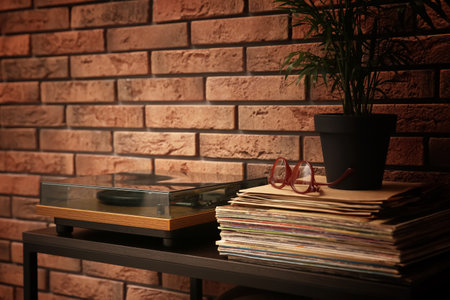 Stylish turntable and vinyl records on shelving unit near red brick wallの写真素材