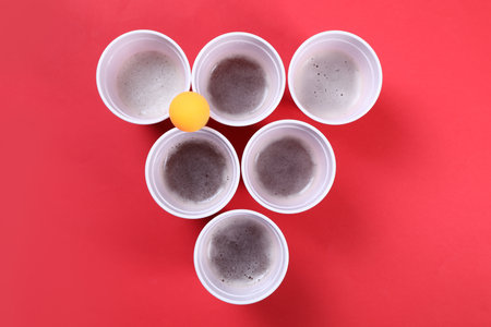 Plastic cups and balls for beer pong on red background, flat layの写真素材