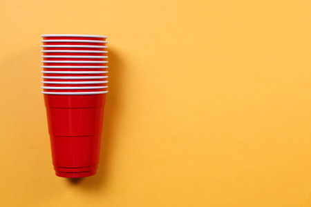 Red plastic cups on orange background, top view with space for textの写真素材