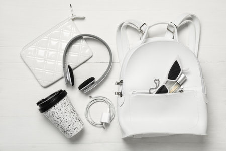 Stylish urban backpack with different items on white wooden background, flat layの写真素材