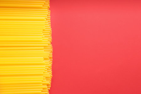 Yellow plastic drinking straws on red background, flat lay. Space for textの写真素材