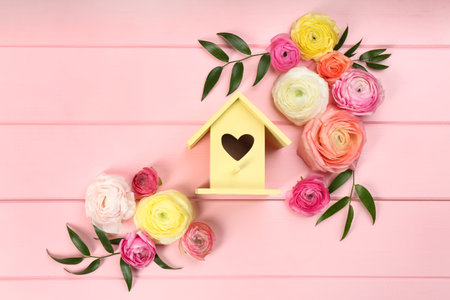 Stylish bird house and fresh eustoma on pink wooden background, flat layの写真素材