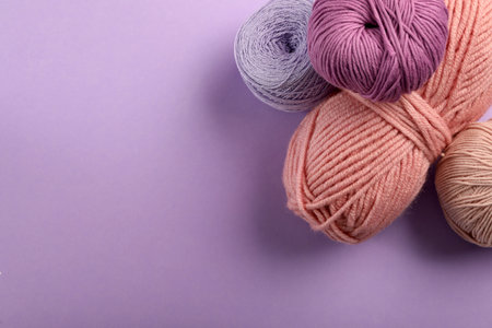 Soft woolen yarns on violet background, flat lay. Space for textの写真素材
