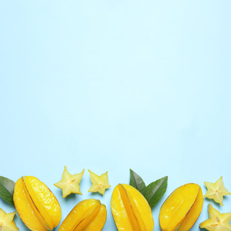 Delicious carambola fruits on light blue background, flat lay. Space for textの写真素材
