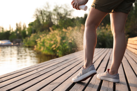 Woman applying insect repellent onto leg at pier, closeup. Space for textの写真素材