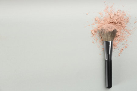Makeup brush and scattered face powder on light gray background, top view. Space for textの写真素材