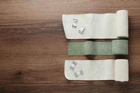 Medical bandage rolls on wooden background, flat lay. Space for textの写真素材