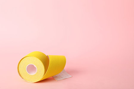 Bright kinesiology tape in roll on pink background. Space for textの写真素材