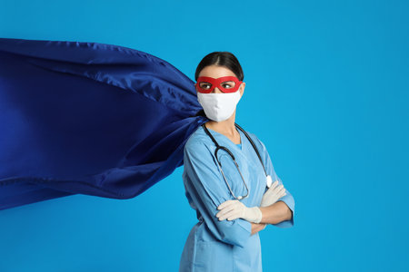 Doctor dressed as superhero posing on light blue background.の写真素材