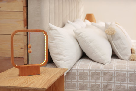 Modern lamp on nightstand near bed in hotelの写真素材