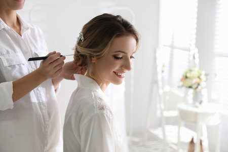 Professional stylist making wedding hairstyle for bride in salonの写真素材