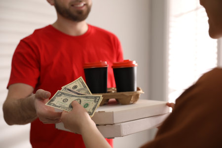 Deliveryman receiving tips from woman indoors, closeupの写真素材