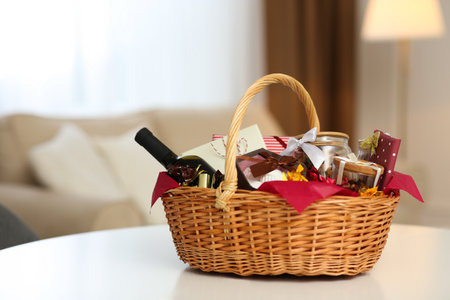 Wicker basket full of gifts on white table in living roomの写真素材